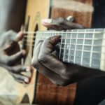 On voit les mains d'un homme en train de jouer de la guitare