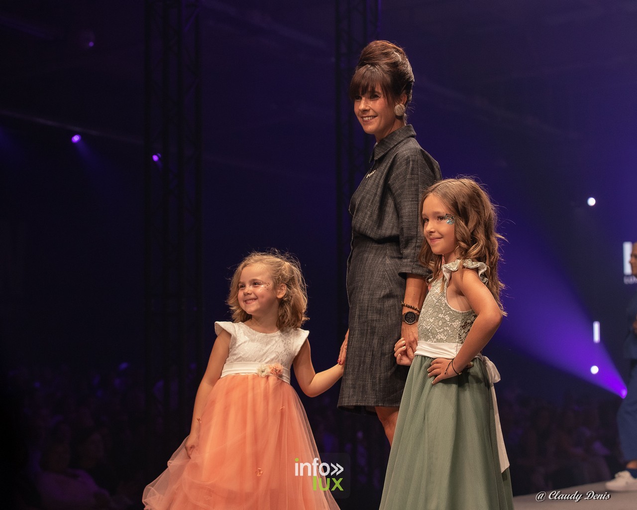 Créatrice et deux fillettes en robes de cérémonie sur le podium de la Lux Fashion Week à Arlon