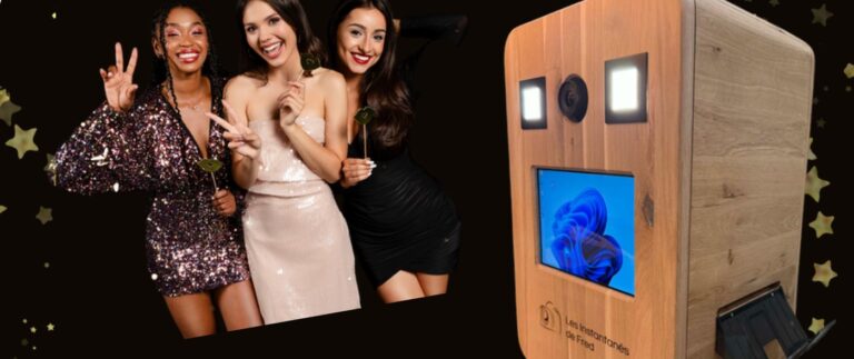 Photobooth Les Instantanes de Fred en bois clair installe a Arlon, avec trois jeunes femmes souriantes posant avec des accessoires fun