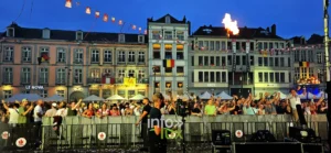 Jets de flammes au-dessus de la foule de la Doudou Sound Party 2026 au crépuscule sur la Grand-Place de Mons