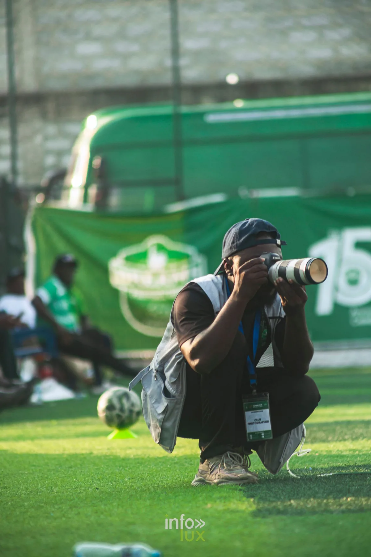 Photographe de club accroupi en bord de terrain de football, téléobjectif blanc, capture de l'action