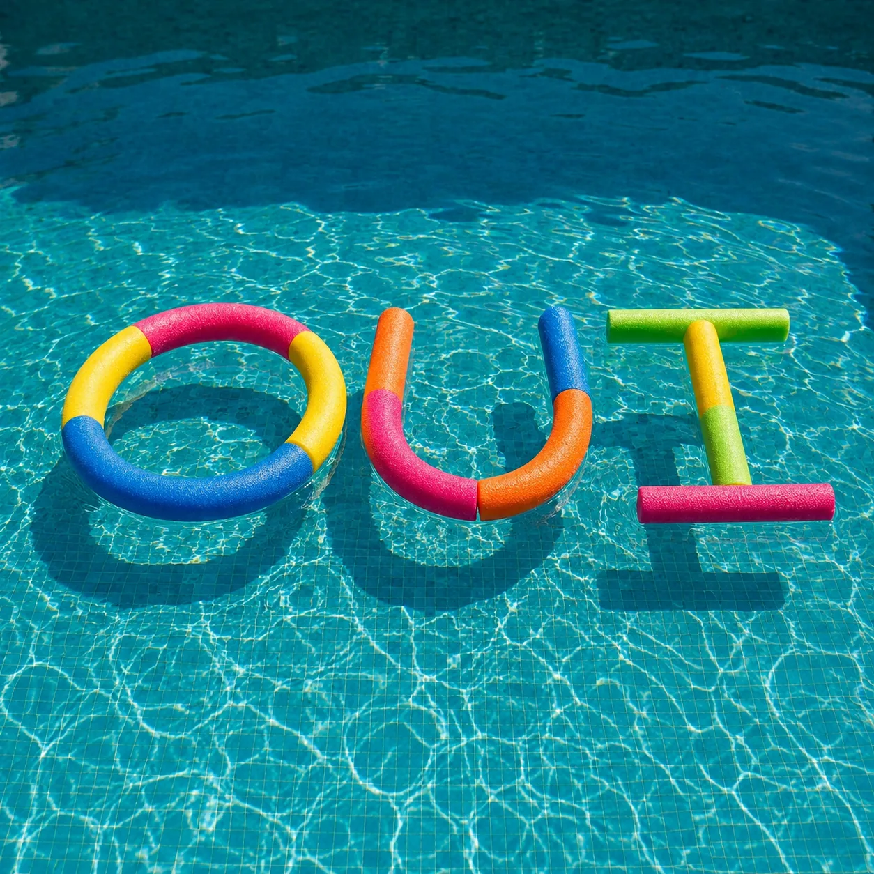 Le mot OUI formé avec des frites de piscine colorées flottant dans une piscine