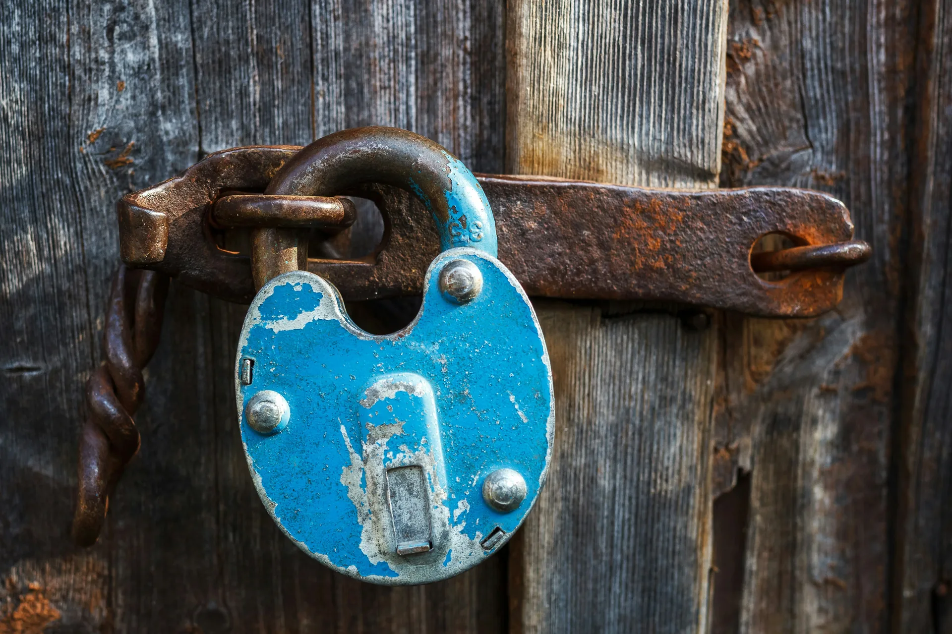 Vieux cadenas bleu rouillé sur une porte en bois, image des verrous intérieurs que l'on installe en soi