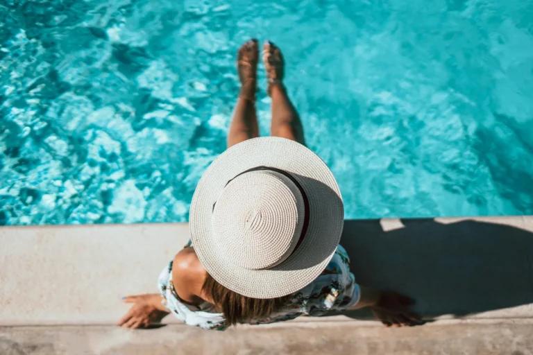 Femme au chapeau de paille se reposant au bord d'une piscine en été