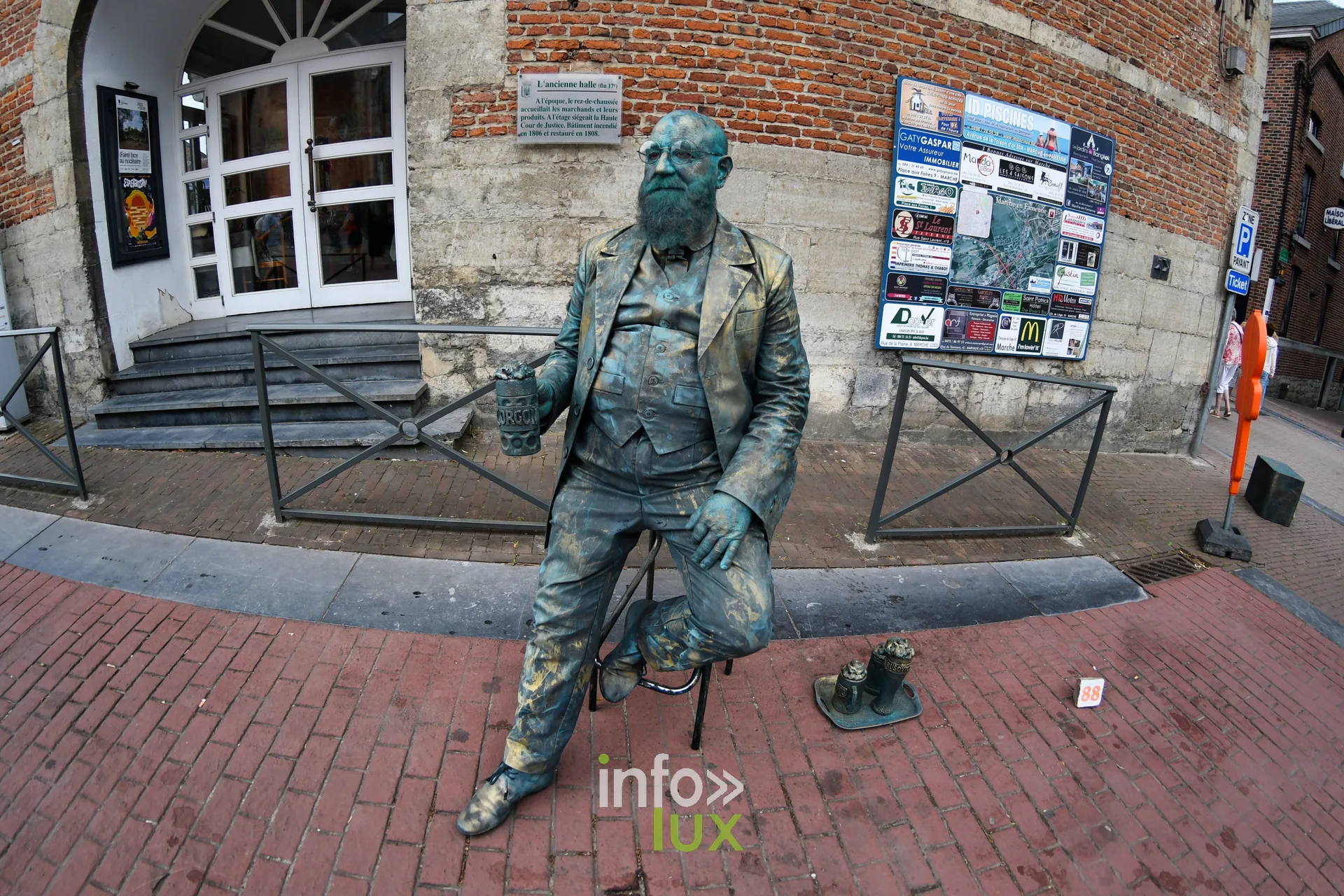 Statue vivante d'un homme barbu à la patine bronze assis près de l'ancienne halle de Marche-en-Famenne