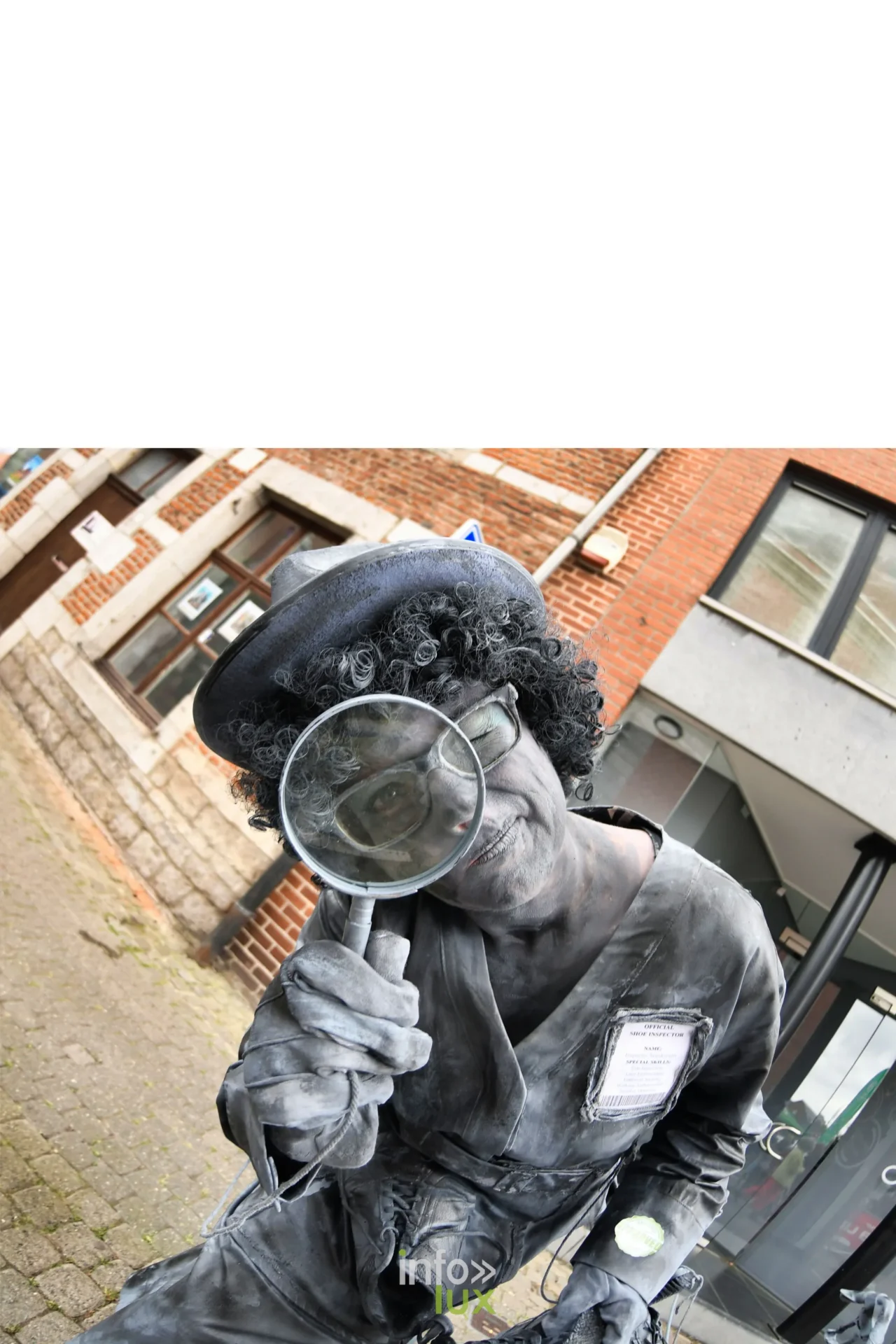 Statue vivante en détective avec loupe et chapeau noir à Marche-en-Famenne