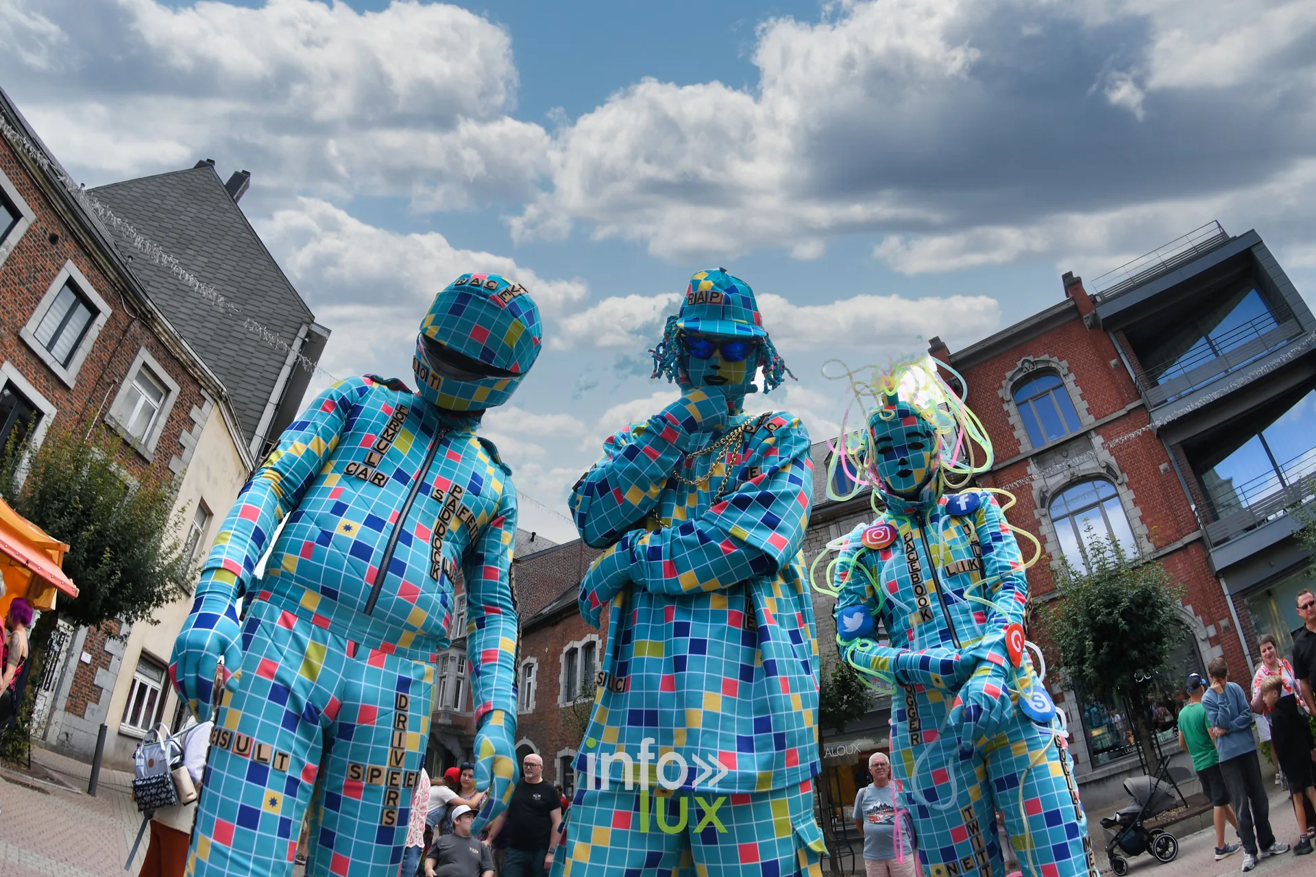 Groupe de statues vivantes en costume à damier bleu dans les rues de Marche-en-Famenne