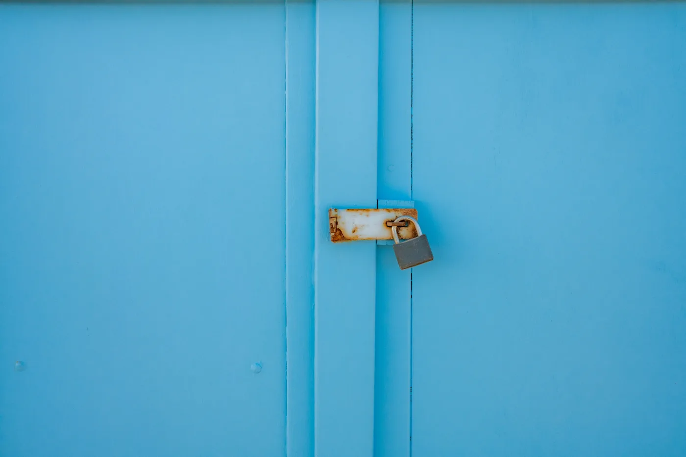 Porte d'un placard bleu fermée par un loquet