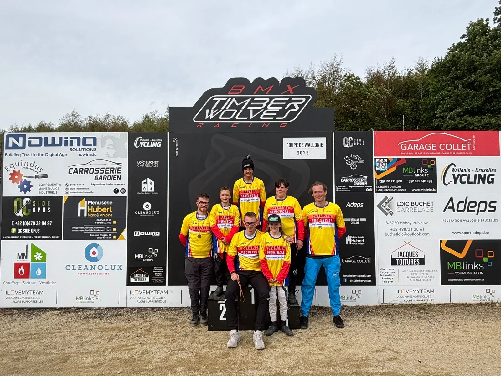 Les sept champions provinciaux du BMX Timberwolves Racing en maillot jaune et rouge sur le podium d'Habay-la-Neuve