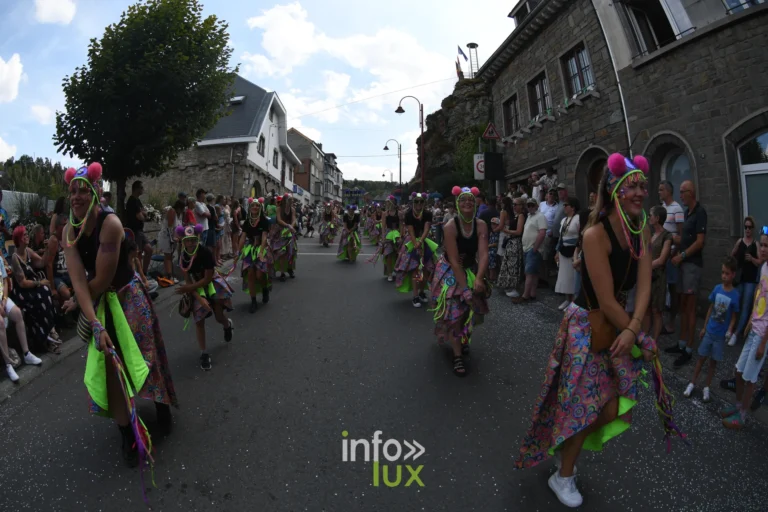Le Grand Cortege du Carnaval du Soleil 2026 descend la rue de Houffalize sous un ciel bleu, public masse sur les trottoirs