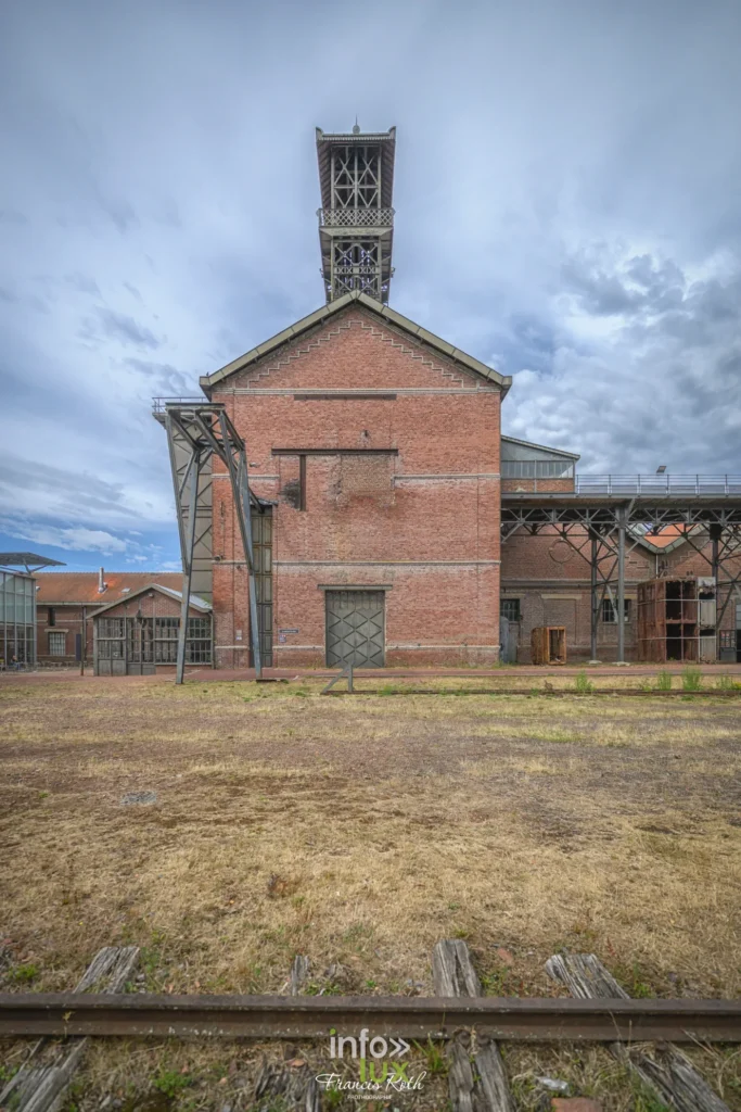 Bâtiment industriel de brique de la fosse Delloye sous un ciel nuageux