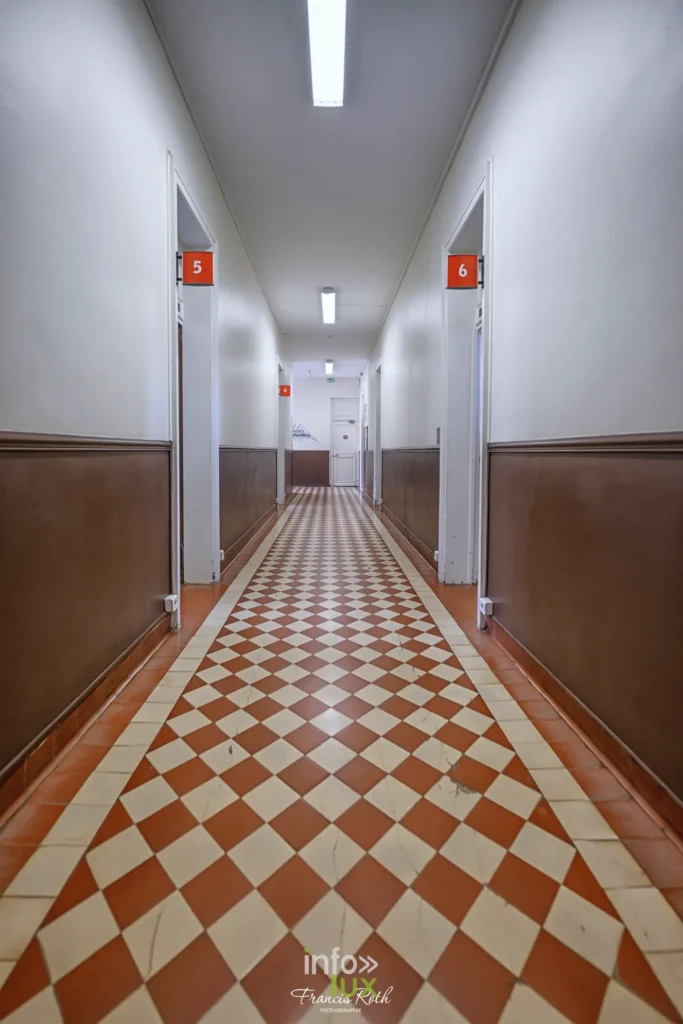 Couloir au sol carrelé rouge et blanc dans un bâtiment du musée