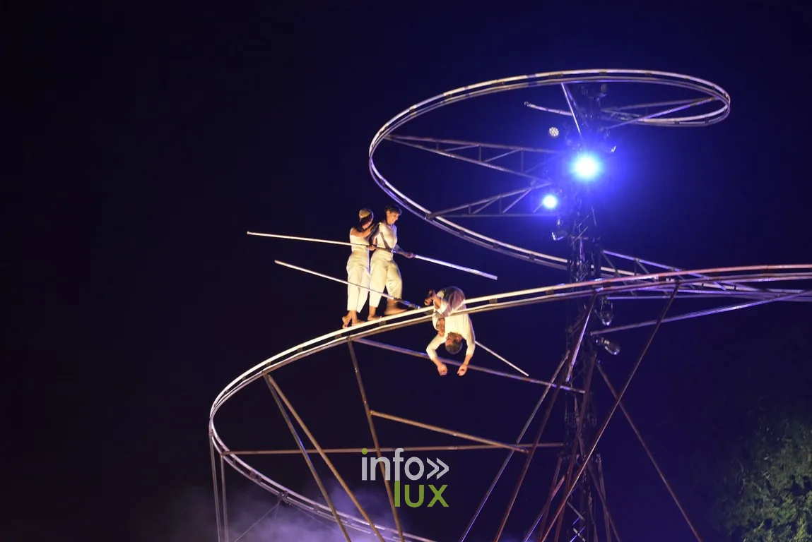 En haut de la spirale, deux silhouettes en équilibre au-dessus du vide.