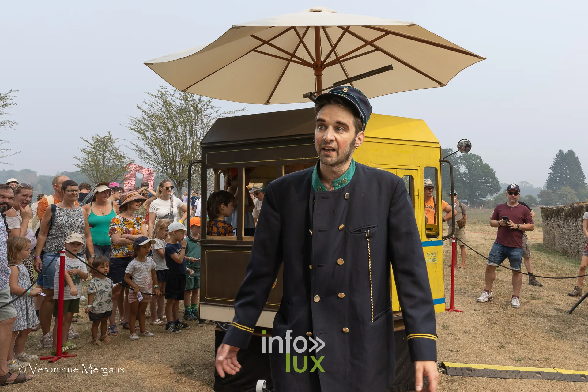 Festival de Chassepierre 2026 — Un tramway jaune posé au milieu du pré, son contrôleur en uniforme et son parasol : le décalage est la règle.