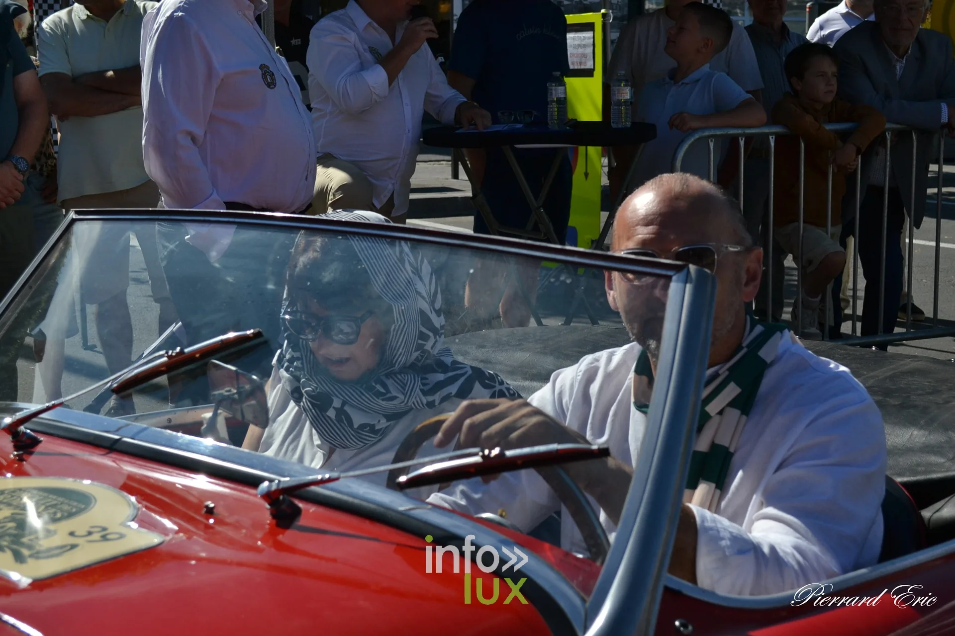 Equipage souriant au volant d'un roadster rouge au depart a Bastogne