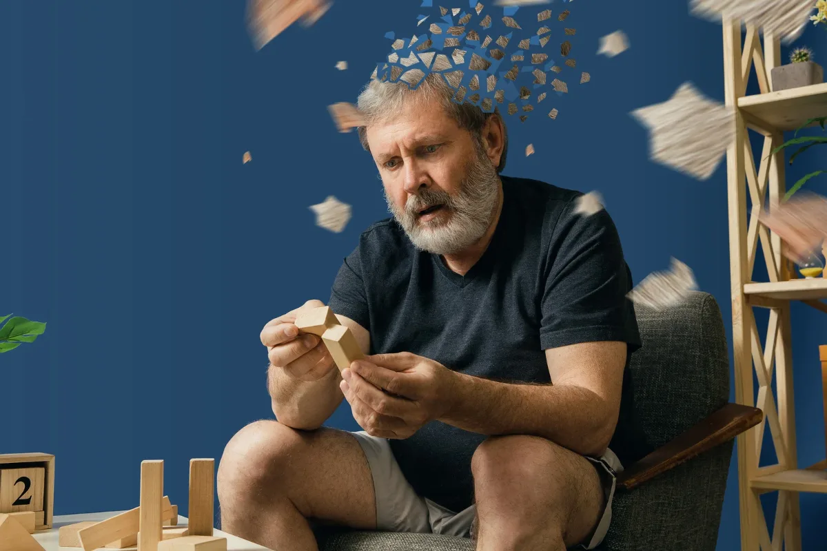 Homme assis jouant avec des cubes de bois, illustration de la perte de memoire