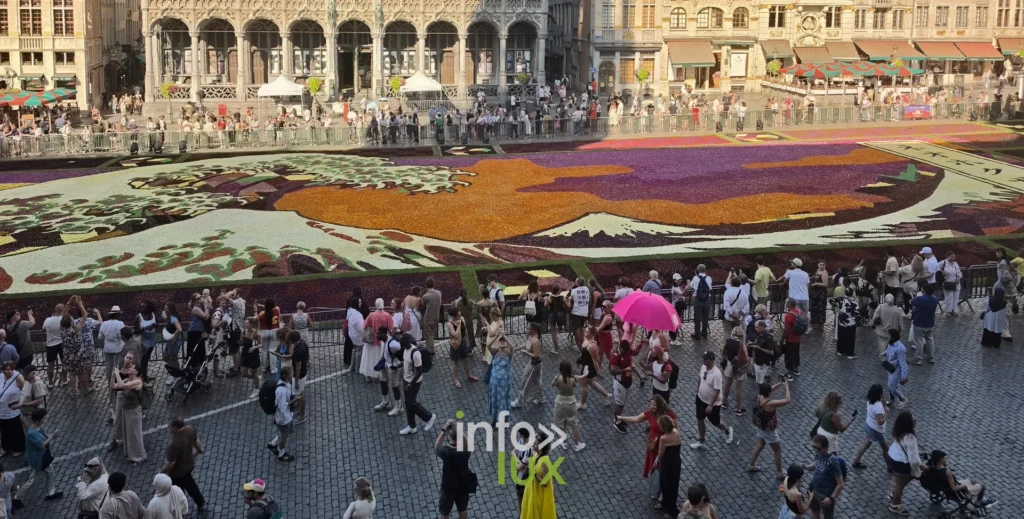Foule sur les pavés de la Grand-Place de Bruxelles autour du tapis floral