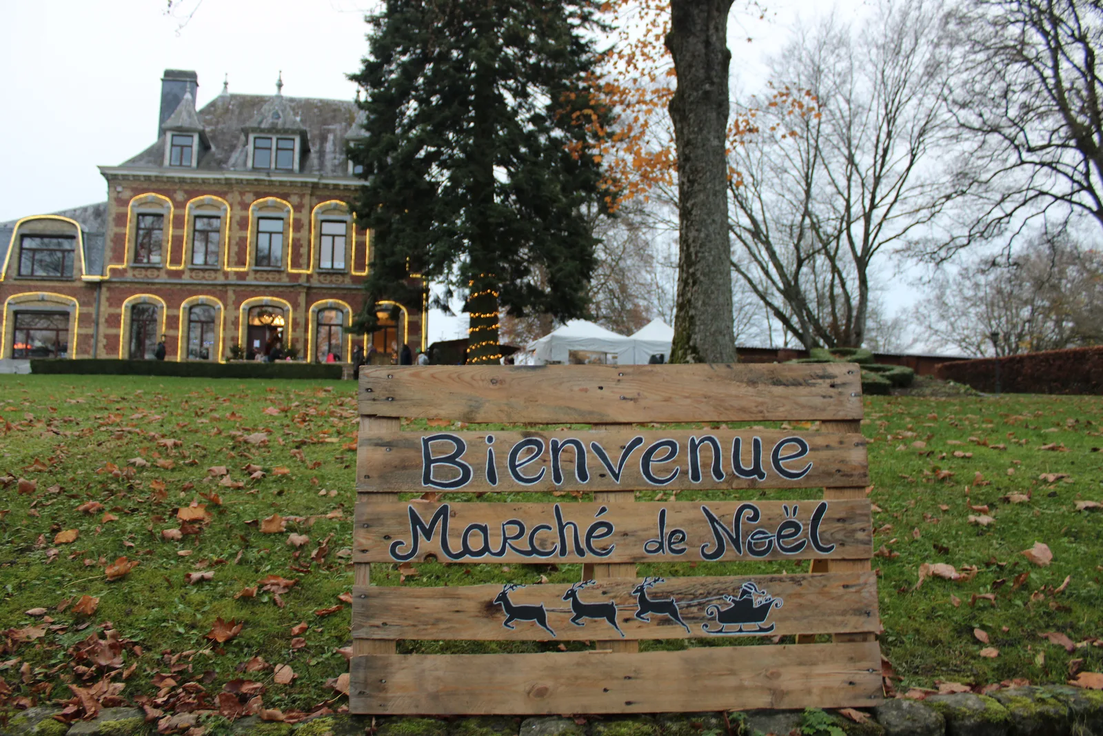 Panneau « Bienvenue au Marché de Noël » en palettes devant le château de Gouvy illuminé