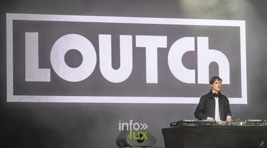 Le DJ Loutch aux platines devant son logo géant, sur la scène du Maredsous Sound Festival
