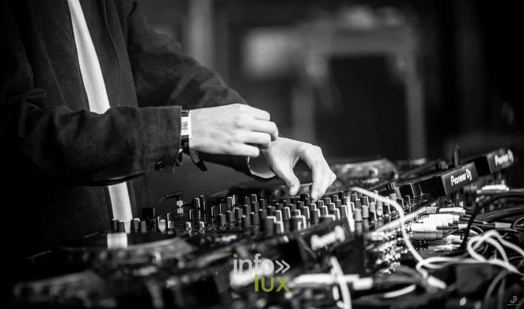 Gros plan noir et blanc sur des mains de DJ réglant les potentiomètres d'une table de mixage