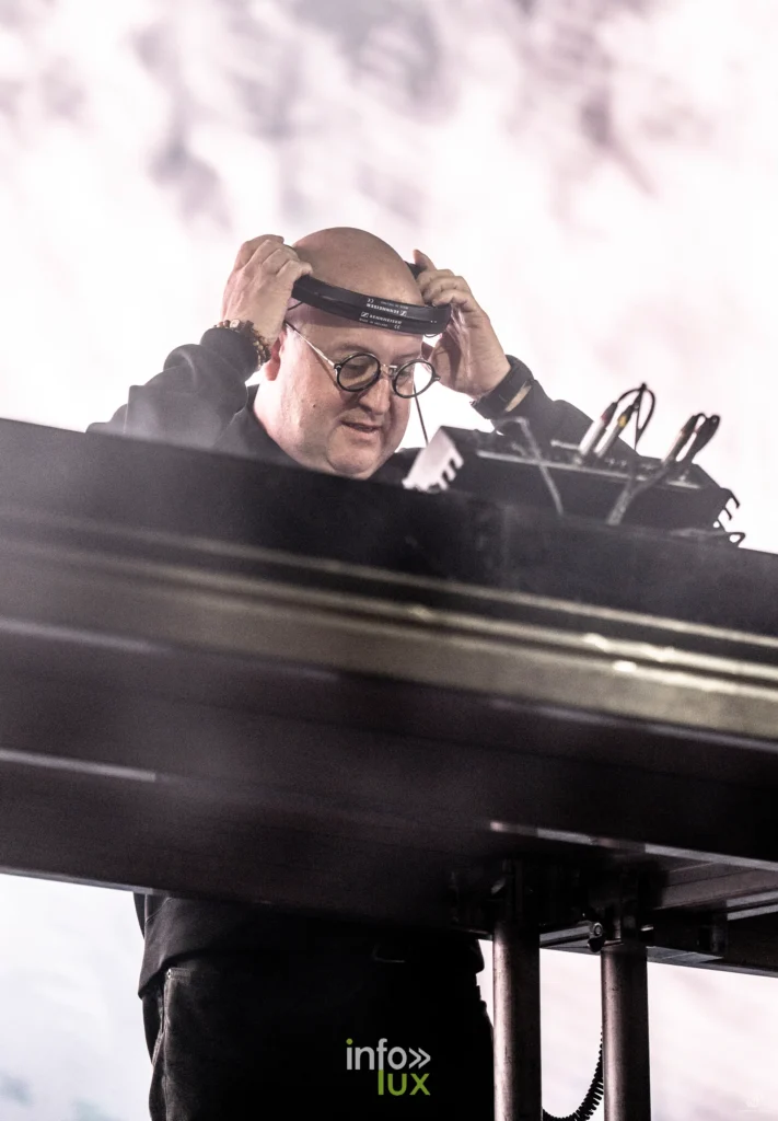 Padre Guilherme, prêtre et DJ, ajuste son casque derrière sa console sur la scène du festival