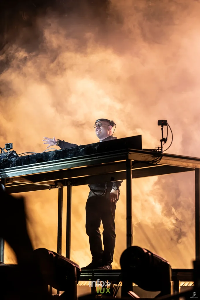 Padre Guilherme sur scène dans un nuage de fumée doré, bras levé