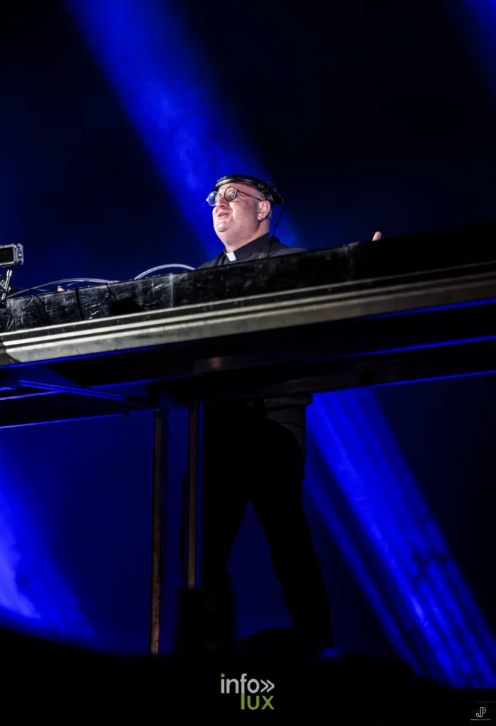 Padre Guilherme derrière sa console, silhouette découpée dans une lumière bleue
