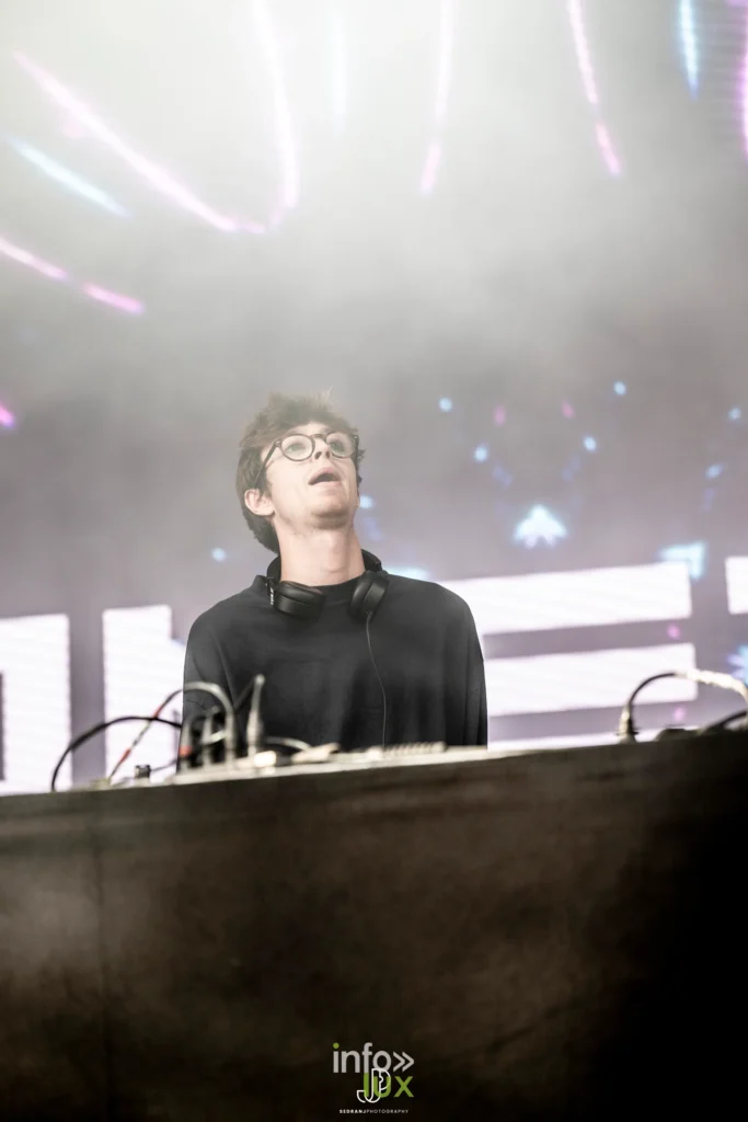 Un DJ en contre-jour dans les faisceaux blancs de la scène du festival