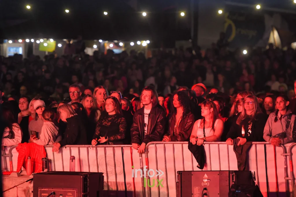 Festivaliers accoudés aux barrières sous la lumière rouge, Summer Lake Festival 2026 à Neufchâteau