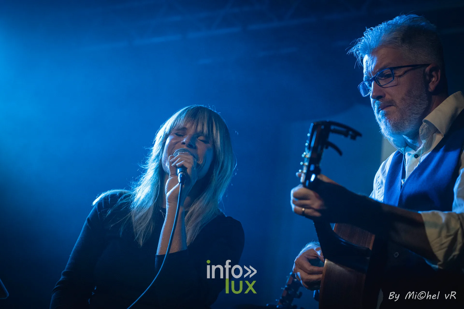 Julie Compagnon chante au micro, Antoine Goudeseune a la guitare derriere elle, sous une lumiere bleue, au Zik-Zak d'Ittre