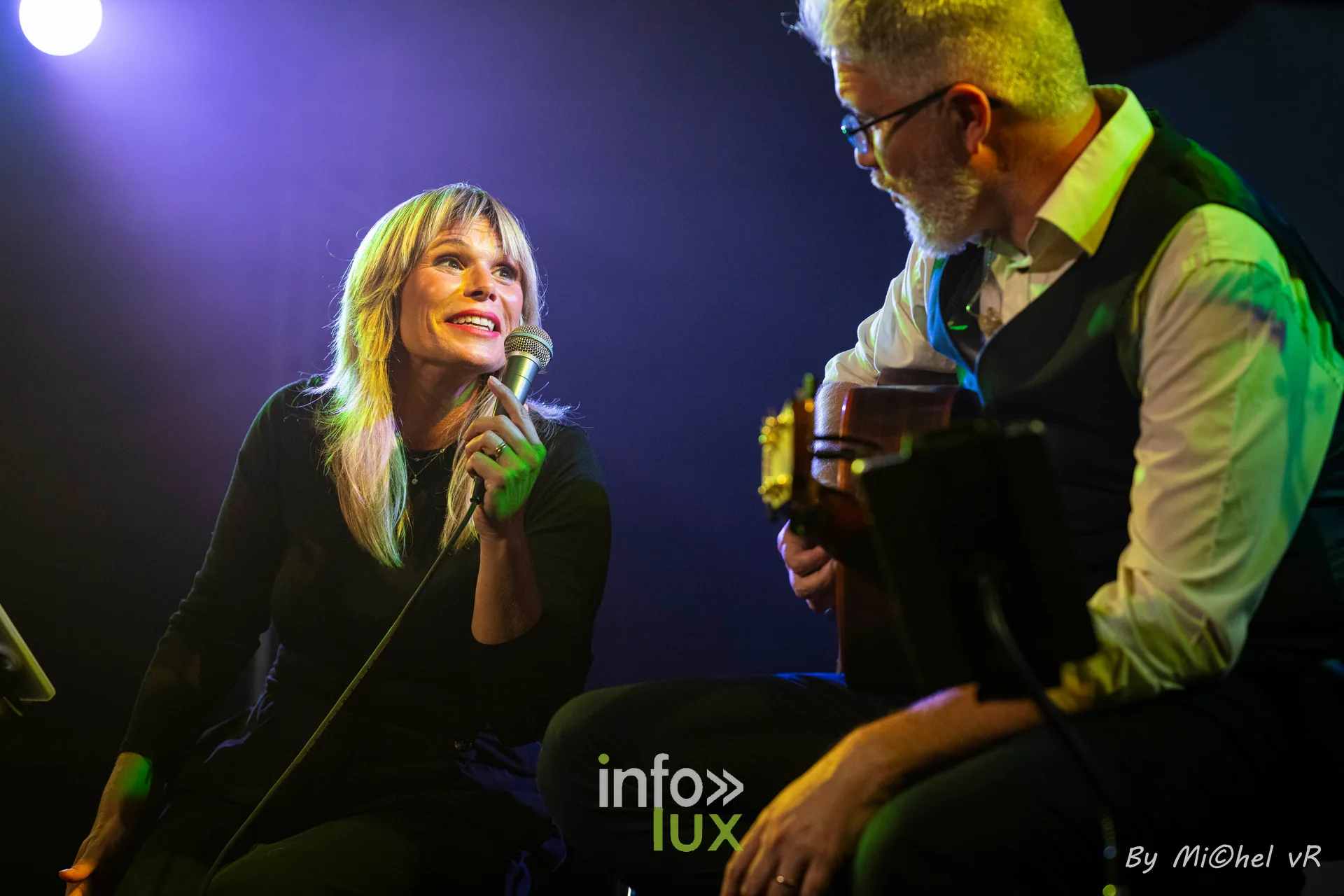 Julie Compagnon assise, micro a la main et sourire aux levres, aux cotes d'Antoine Goudeseune a la guitare