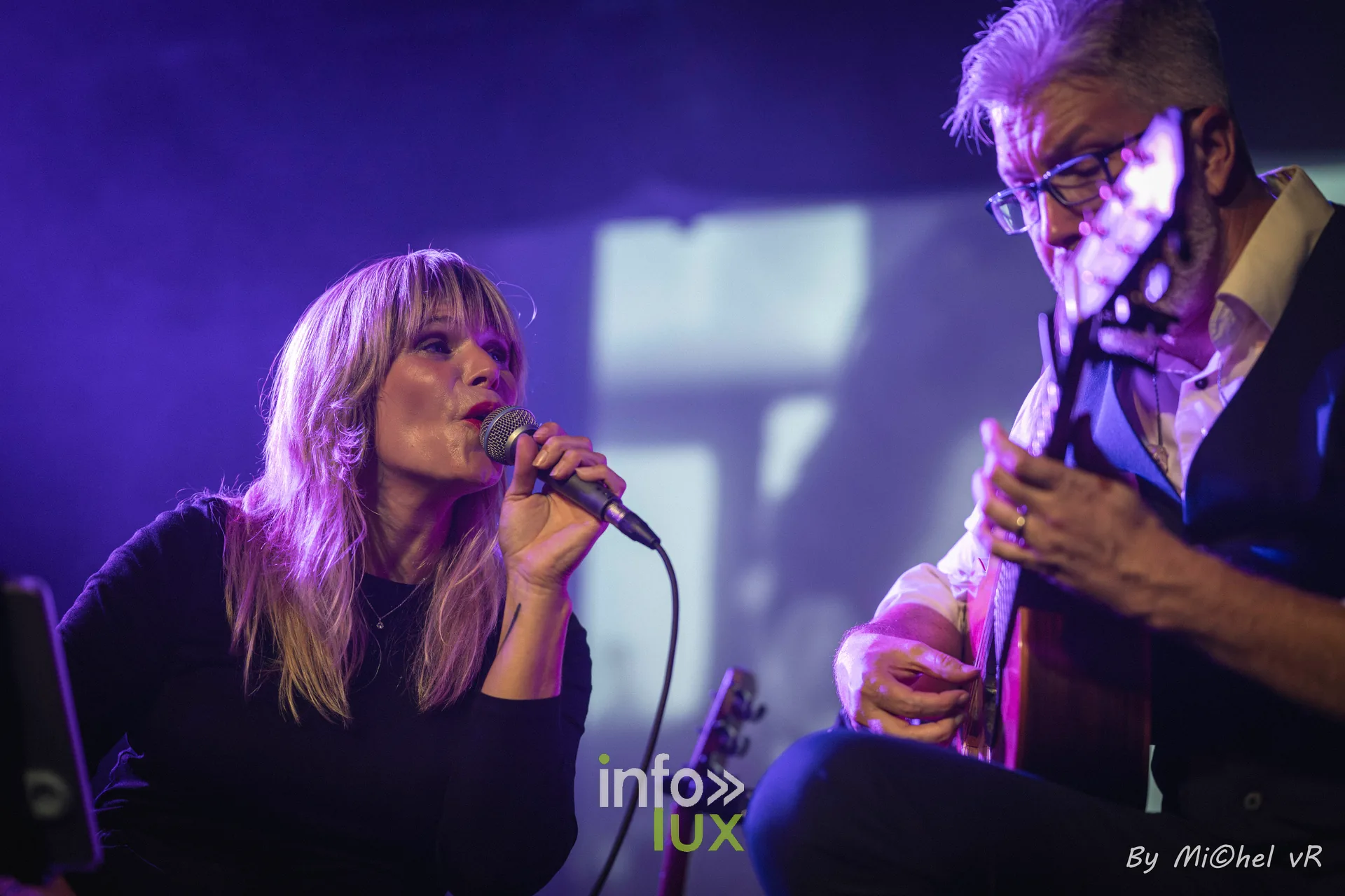 Julie Compagnon au micro et Antoine Goudeseune a la guitare, cadres serres sous une lumiere violette
