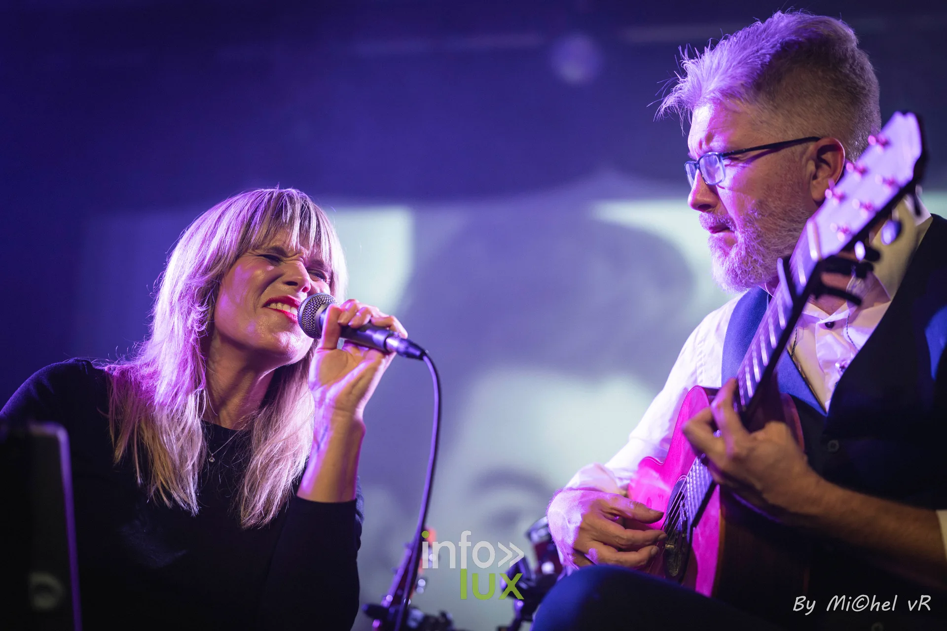 Julie Compagnon souriante au micro pendant qu'Antoine Goudeseune joue de la guitare, lumiere violette