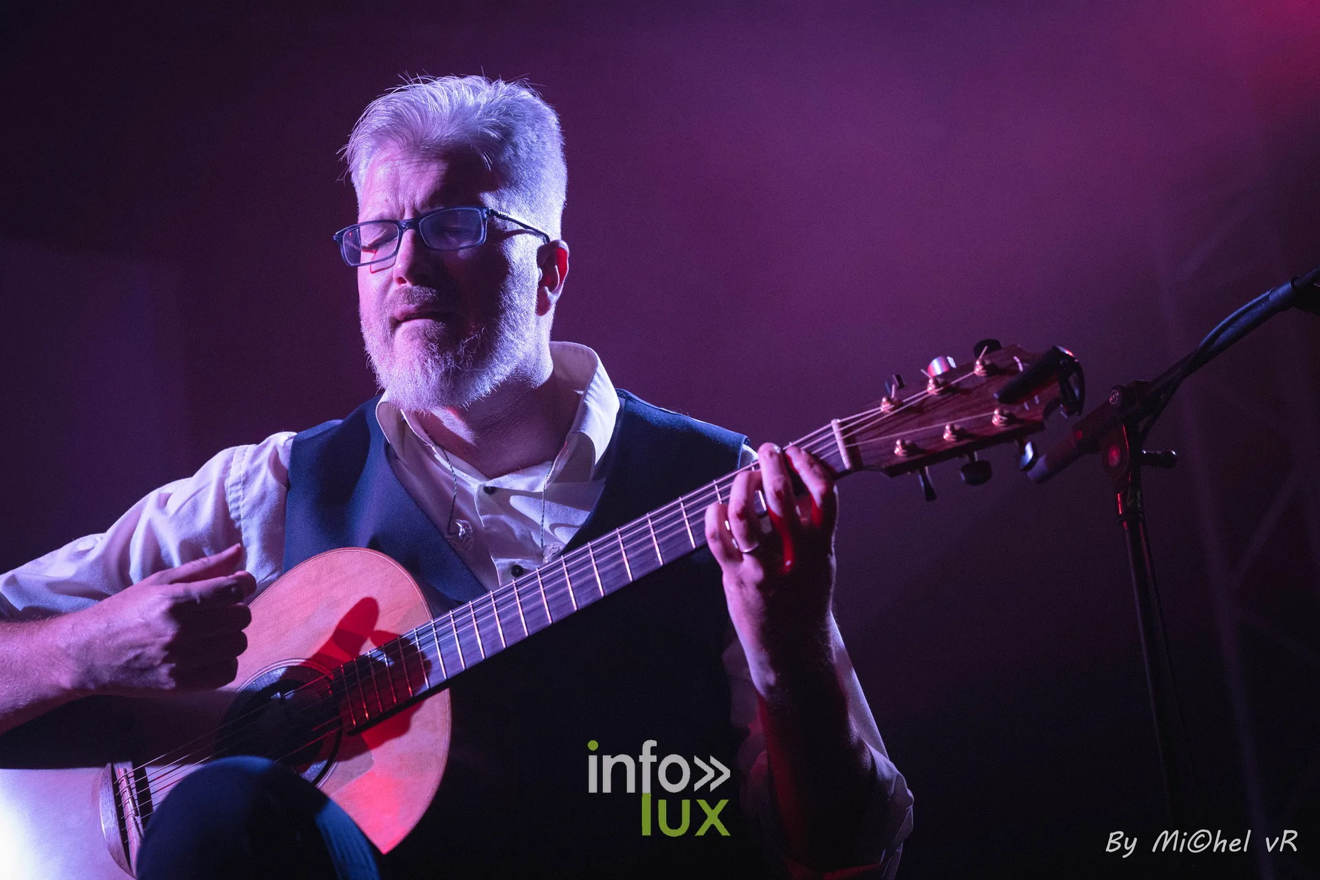 Gros plan sur Antoine Goudeseune et sa guitare acoustique sous une lumiere rose