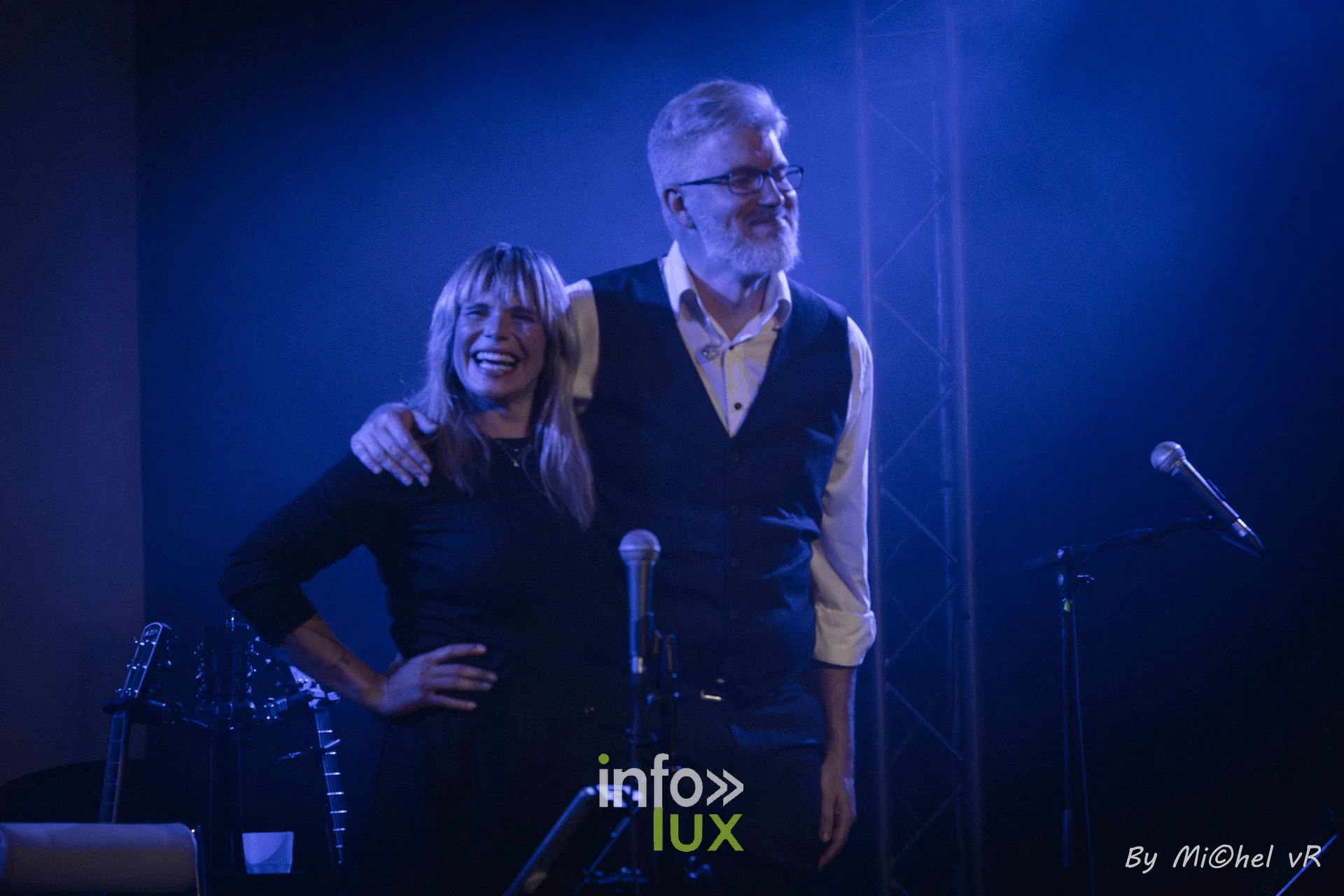 Julie Compagnon et Antoine Goudeseune debout et souriants saluent le public a la fin du concert, sous une lumiere bleue
