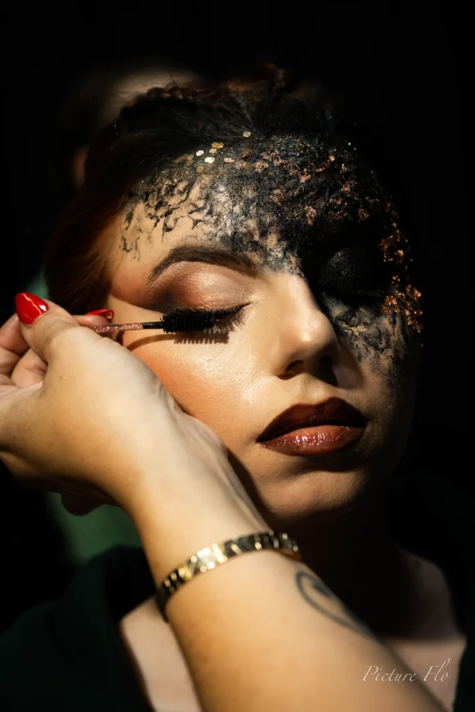 Pose du mascara sur un visage au front couvert de pâte noire, coulisses de la Lux Fashion Week 2026, Arlon