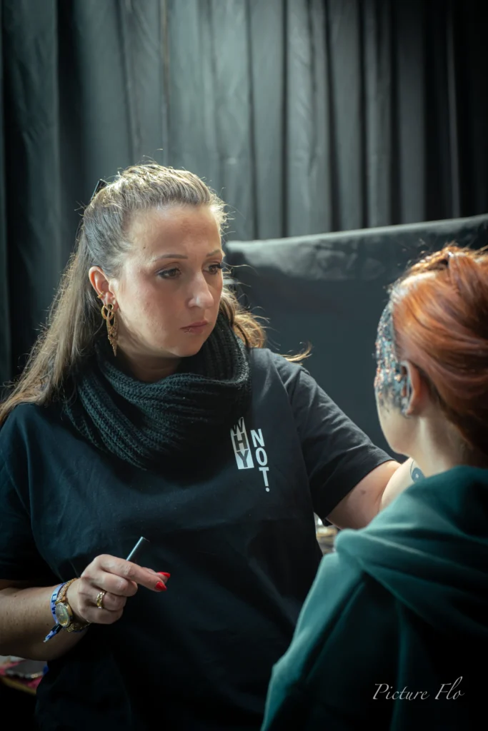 Maquilleuse au travail face à Marine, coulisses du show « Les talents de l’ombre », Lux Fashion Week 2026, Arlon