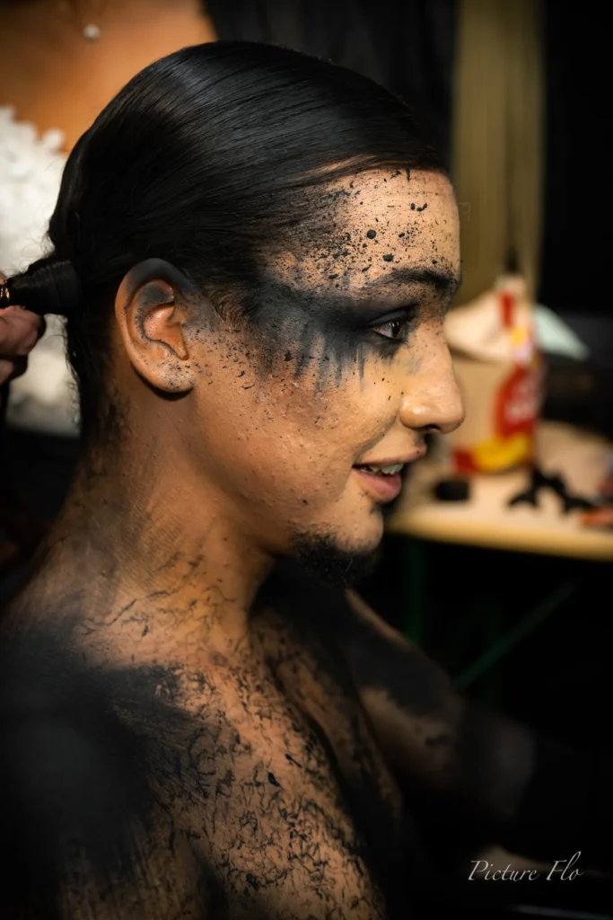 Youness en coulisses, visage et torse couverts de maquillage noir craquelé, Lux Fashion Week 2026, Arlon