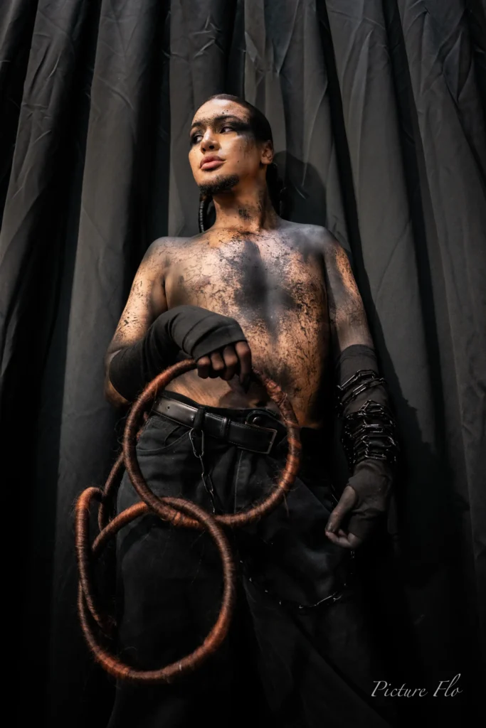 Youness torse nu au maquillage craquelé, anneaux en cheveux en main, coulisses de la Lux Fashion Week 2026, Arlon