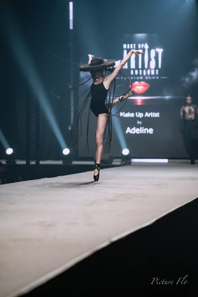 Léa, ballerine, jambe levée sur le podium sous le chapeau de tresses, Lux Fashion Week 2026, Arlon