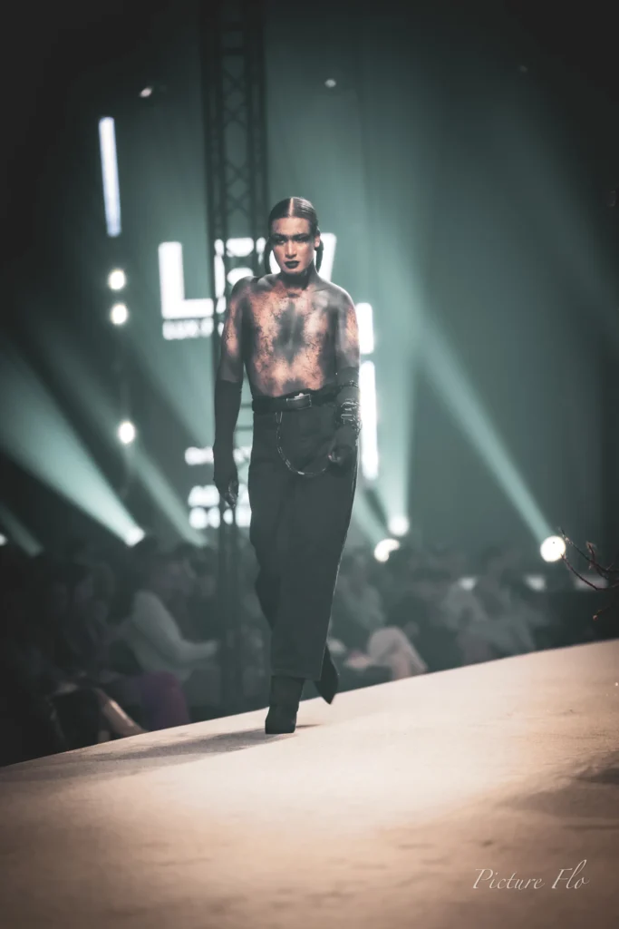 Youness sur le podium, torse nu au maquillage craquelé, gants noirs, Lux Fashion Week 2026, Arlon
