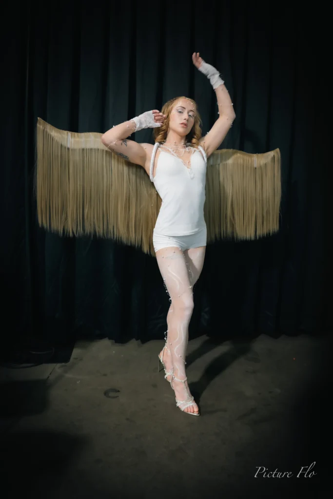 Nova bras levé, ailes dorées déployées, portrait en studio, Lux Fashion Week 2026, Arlon