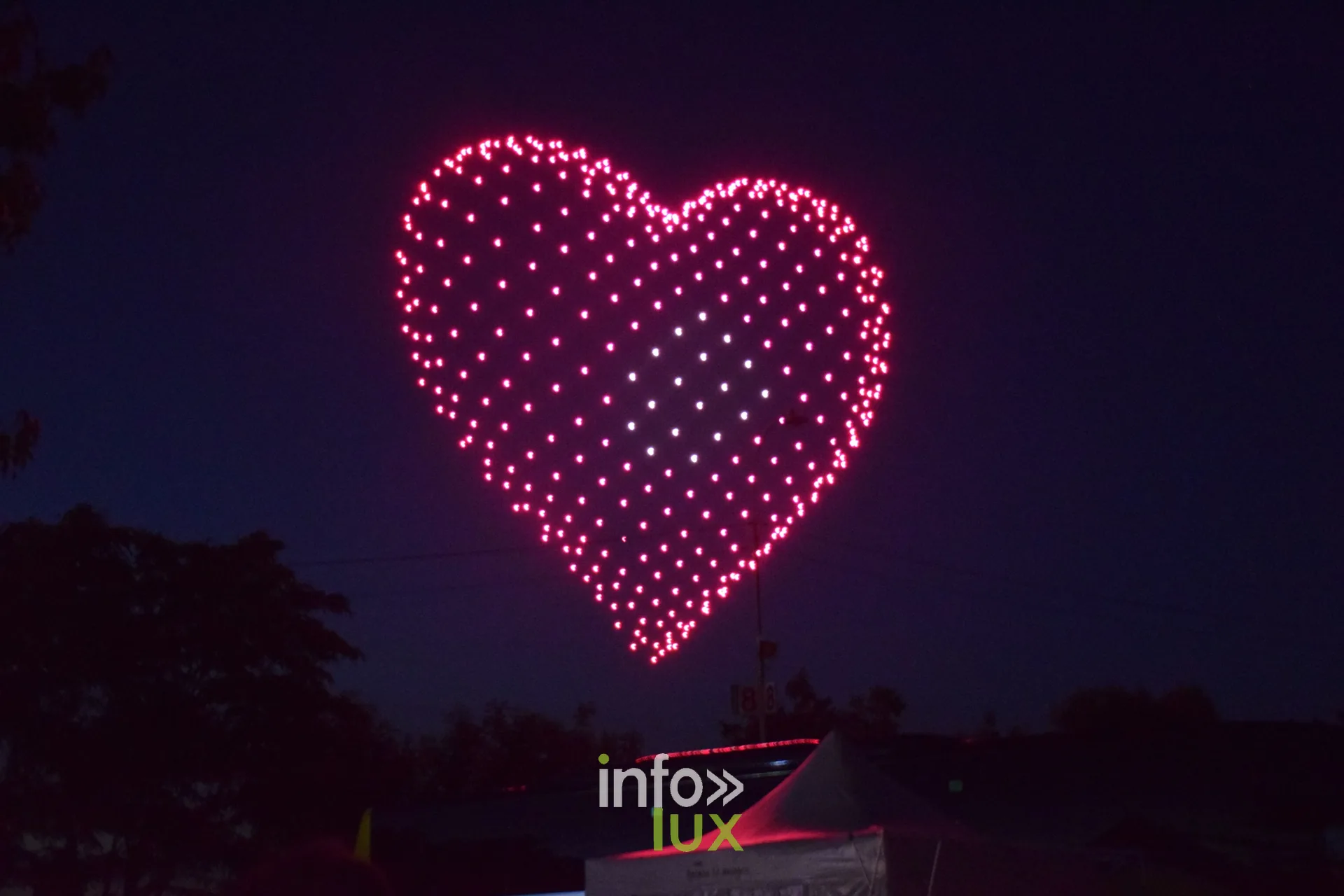 Coeur rose forme par des drones lumineux dans le ciel