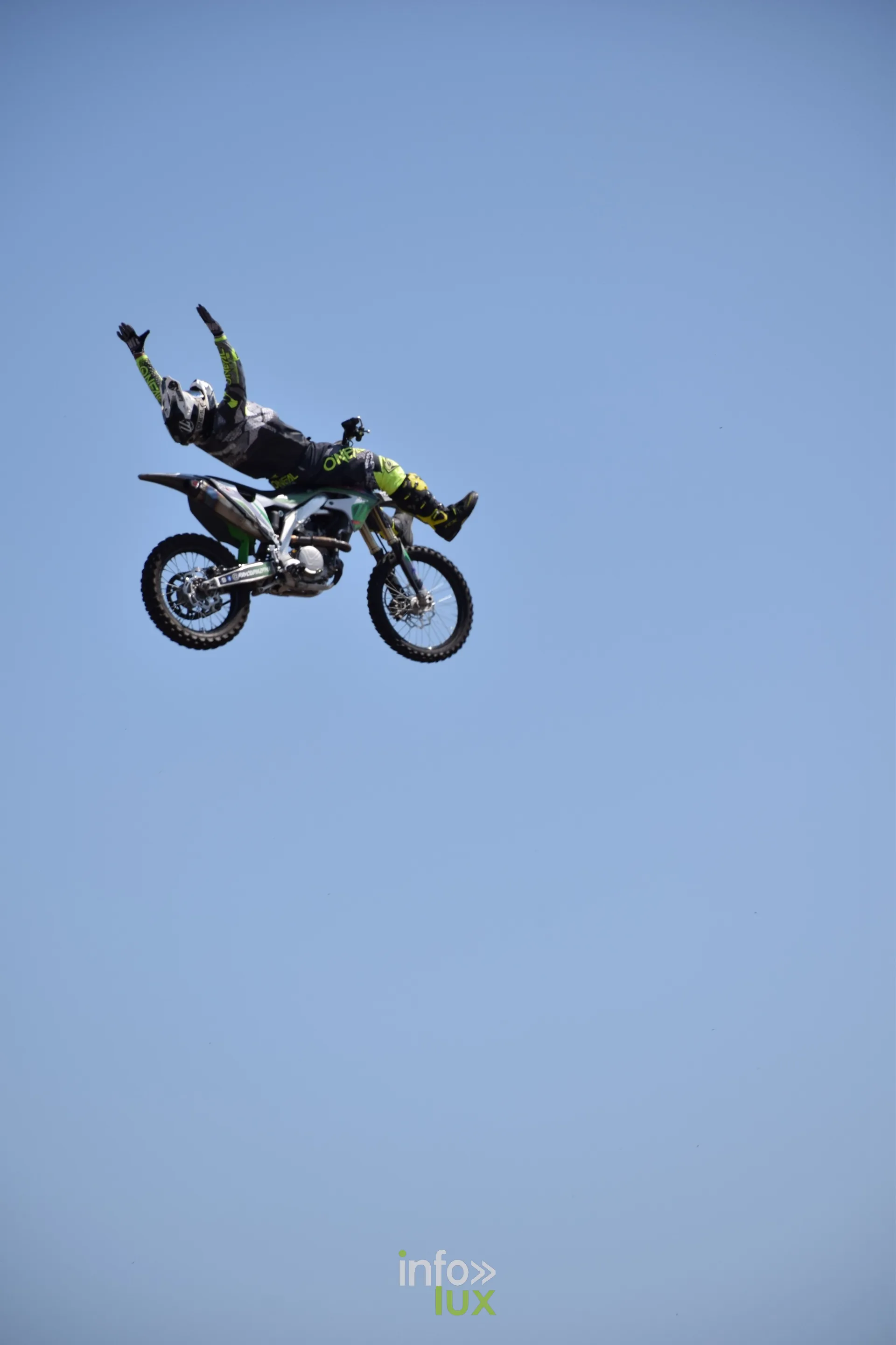 Motard de freestyle en plein saut, silhouette sur ciel bleu
