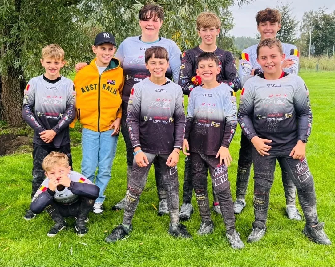 Les jeunes pilotes du BMX Timberwolves Racing Habay en maillot du club, dans l’herbe à Wachtebeke