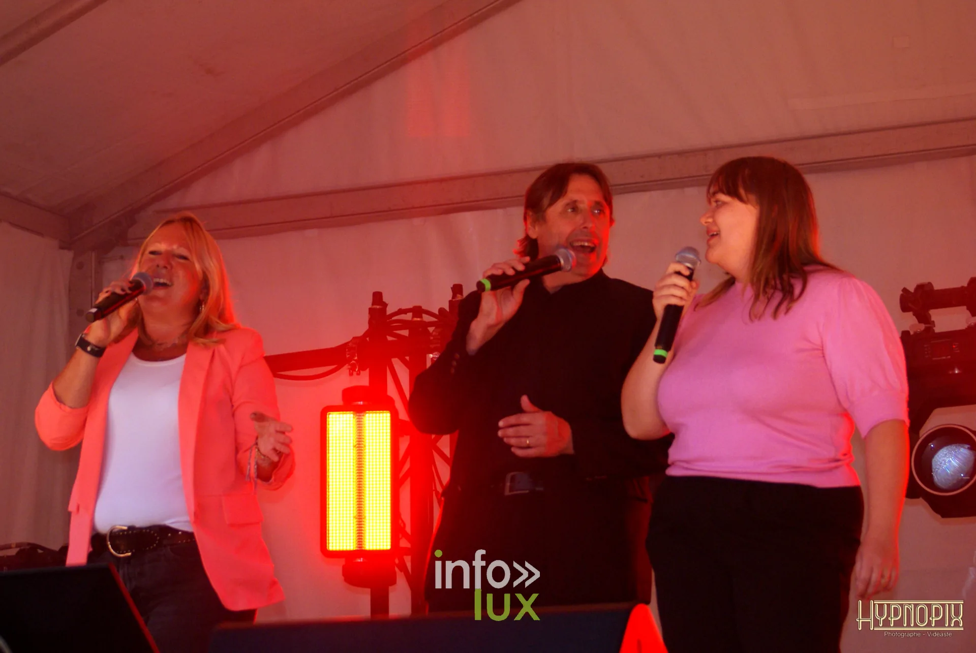 Trois chanteurs au micro lors du concert de reprises de la Braderie de Braine-l’Alleud