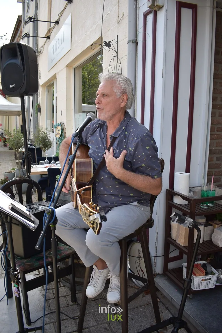 Un chanteur guitariste installé en terrasse pendant la braderie