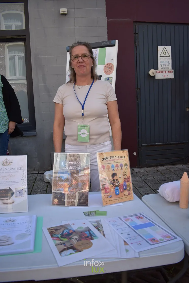 Une autrice pose devant le présentoir de ses livres pour enfants