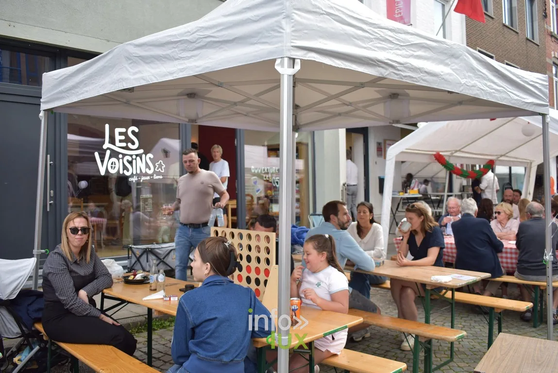 Des visiteurs attablés au stand « Les Voisins » sous chapiteau