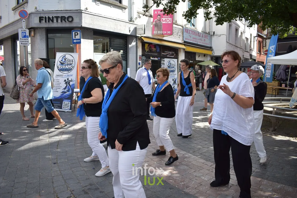 Un groupe en tenue blanche et bleue traverse la braderie